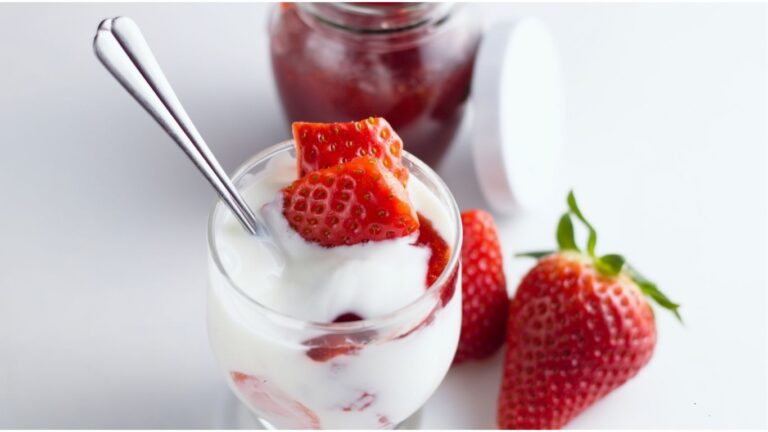 A bowl of yogurt topped with fresh strawberries, showcasing a creamy dessert.